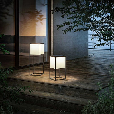 Two outdoor lamps on a wooden deck at night.