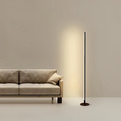 Modern floor lamp next to a beige sofa in a minimalistic room.